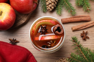 Photo of Hot mulled cider, ingredients and fir branches on wooden table, flat lay