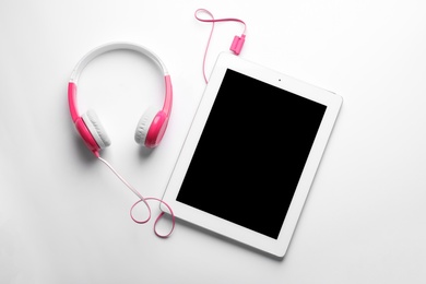 Stylish headphones and modern tablet on white background, top view. Space for text