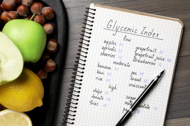 Photo of Notebook with products of low, moderate and high glycemic index, pen and food on wooden table, flat lay