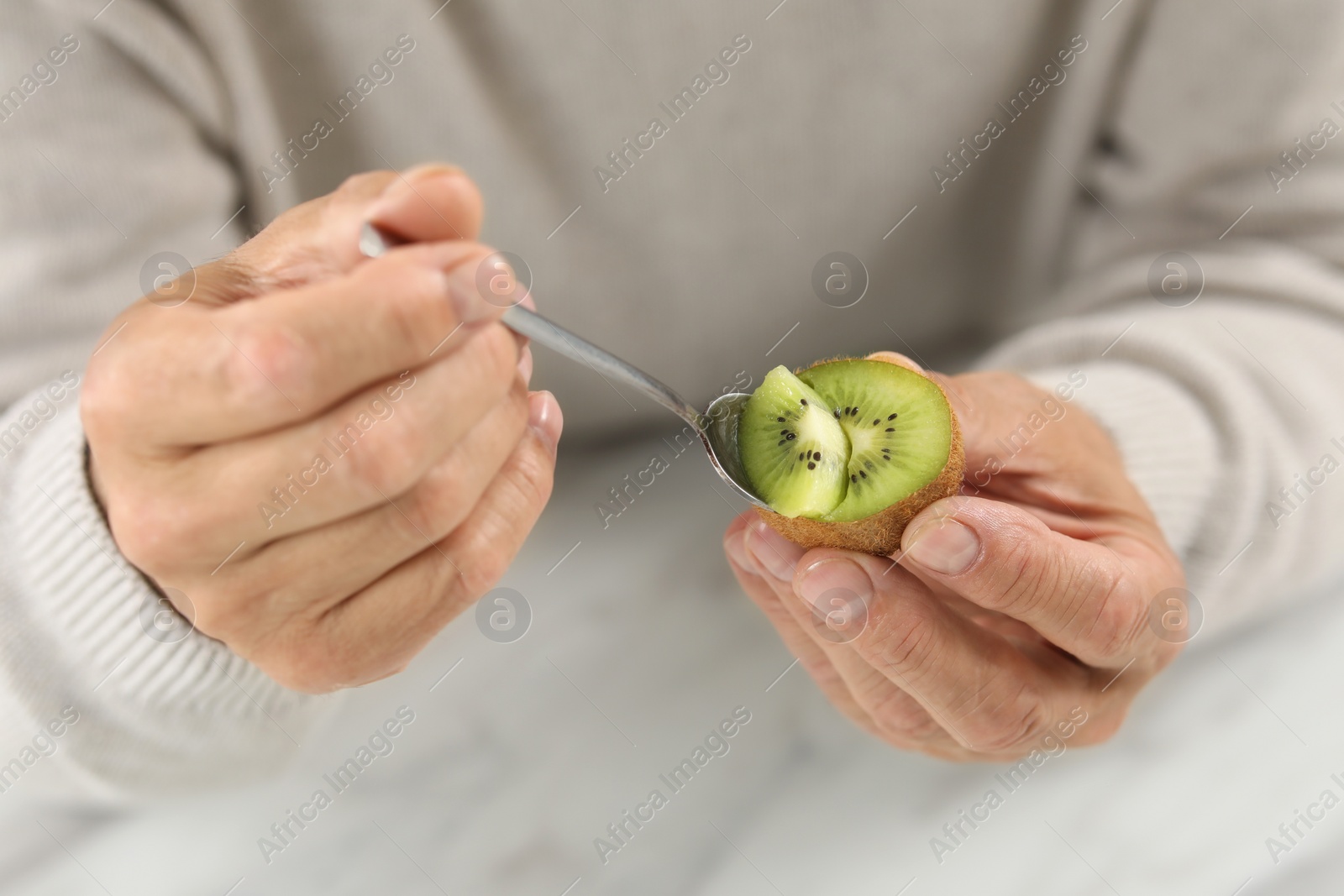 Photo of Man eating kiwi with spoon, closeup view