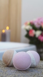 Photo of Colorful bath bombs on wicker mat in bathroom