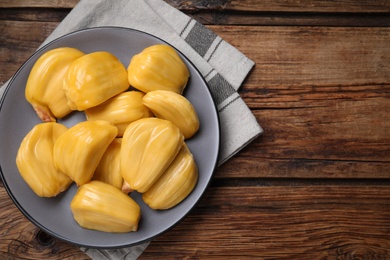 Photo of Delicious exotic jackfruit bulbs on wooden table, top view. Space for text