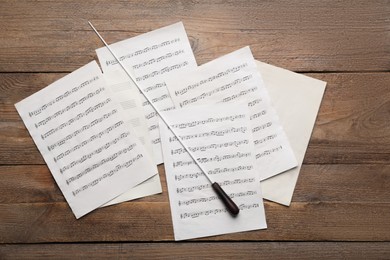 Photo of Conductor's baton and sheet music on wooden table, flat lay