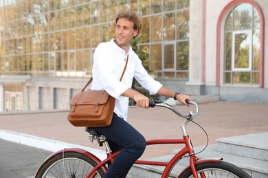 Photo of Attractive man riding bike on city street