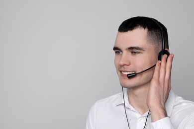 Photo of Hotline operator with headset on light grey background, space for text