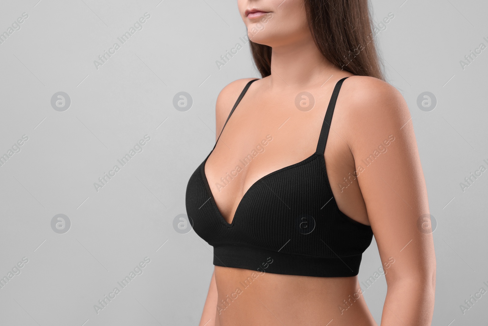 Photo of Woman with beautiful breast on light grey background, closeup. Space for text