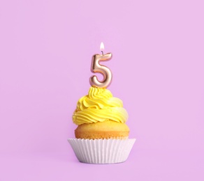 Photo of Birthday cupcake with number five candle on violet background