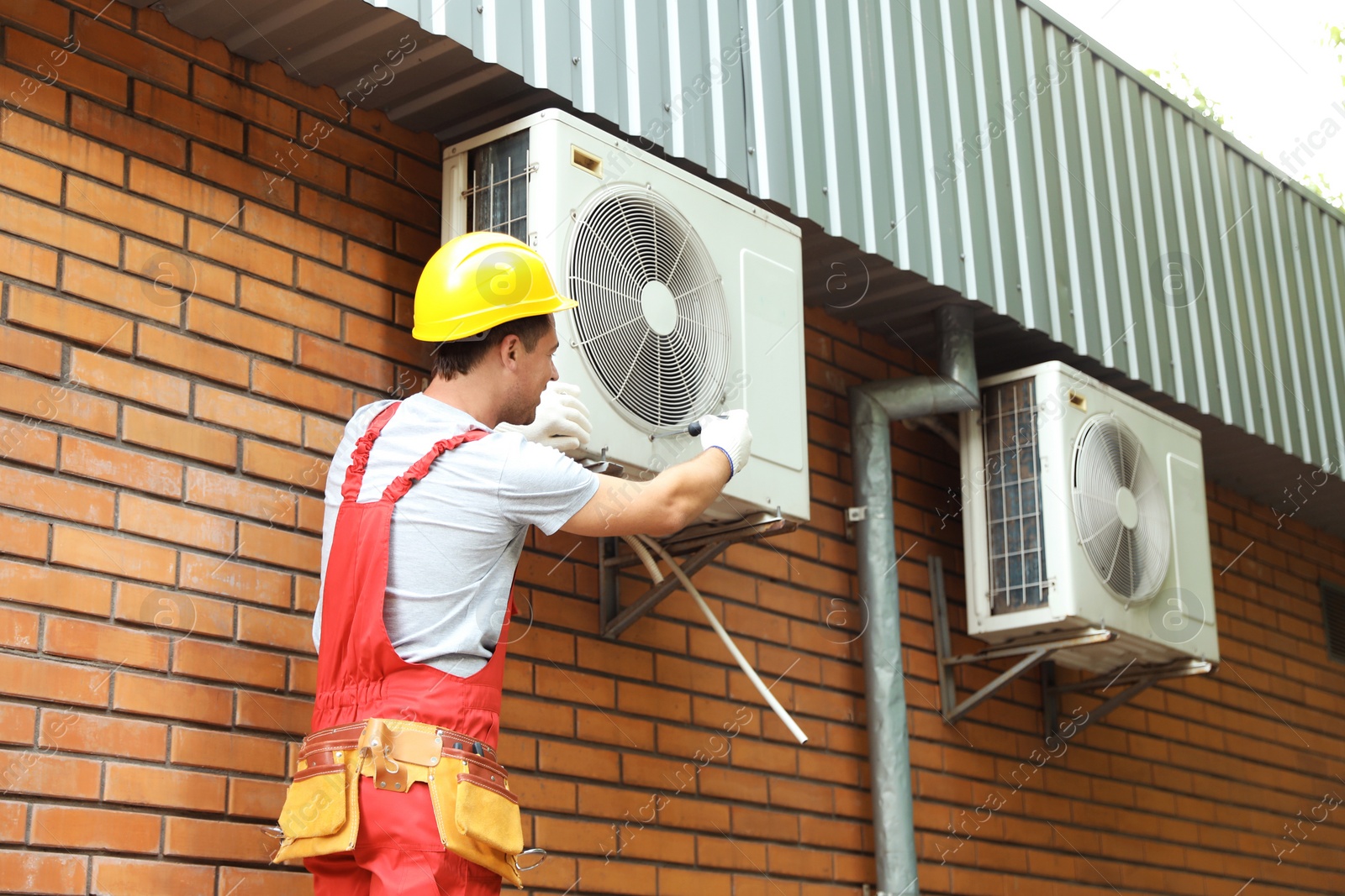 Photo of Male technician fixing air conditioner outdoors