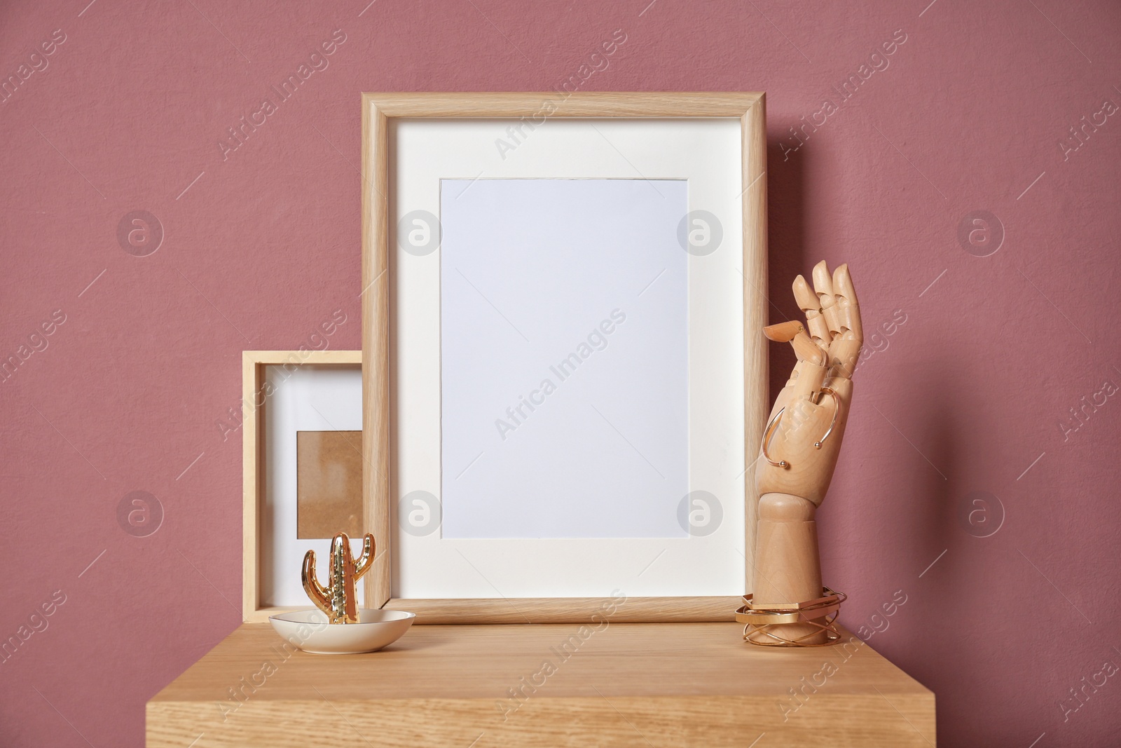 Photo of Mockup of blank frame and wooden hand on table