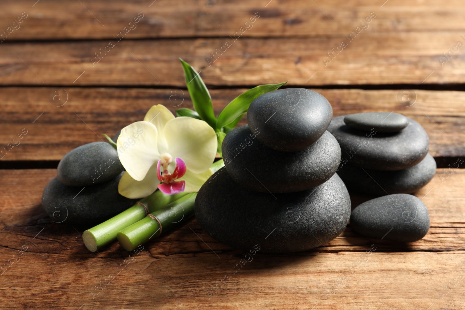 Photo of Spa stones, bamboo stems and beautiful orchid flower on wooden table