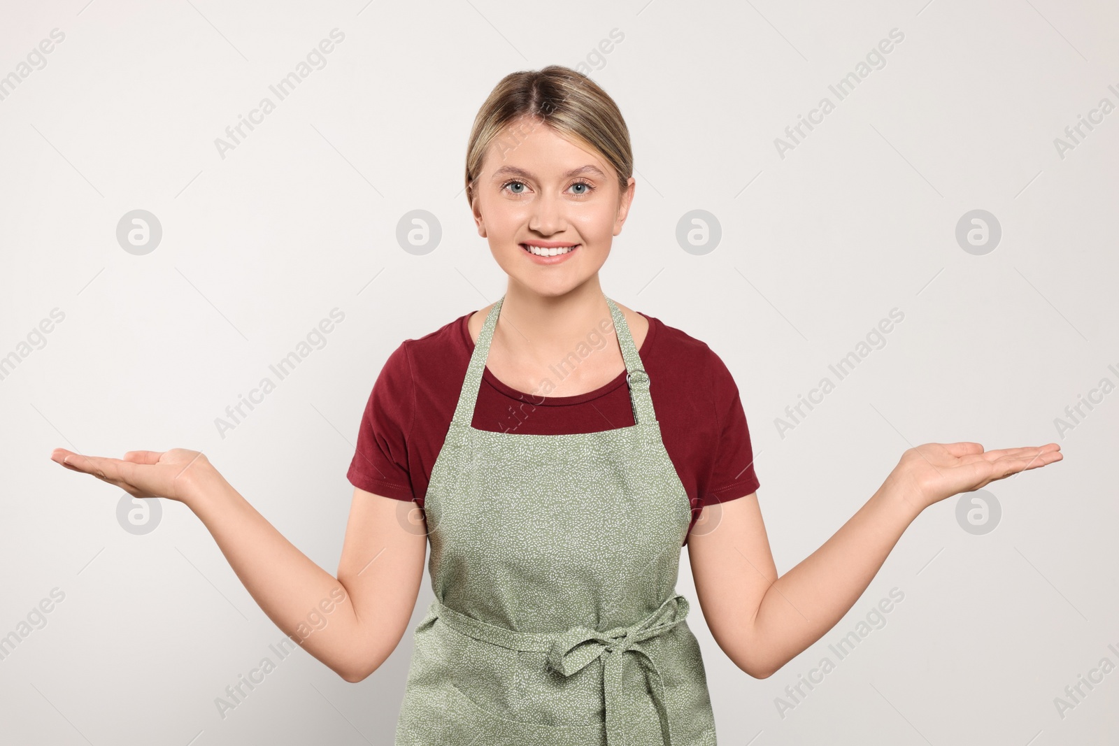 Photo of Beautiful young woman in clean apron on light grey background