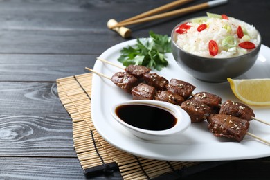 Photo of Tasty chicken meat glazed in soy sauce served with rice on black wooden table, closeup. Space for text