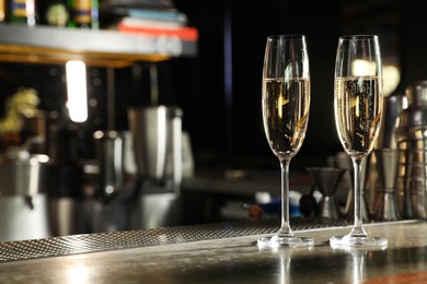 Photo of Glasses of champagne on counter in bar. Space for text