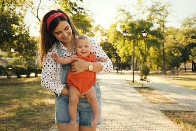 Young mother with her cute baby in park on sunny day