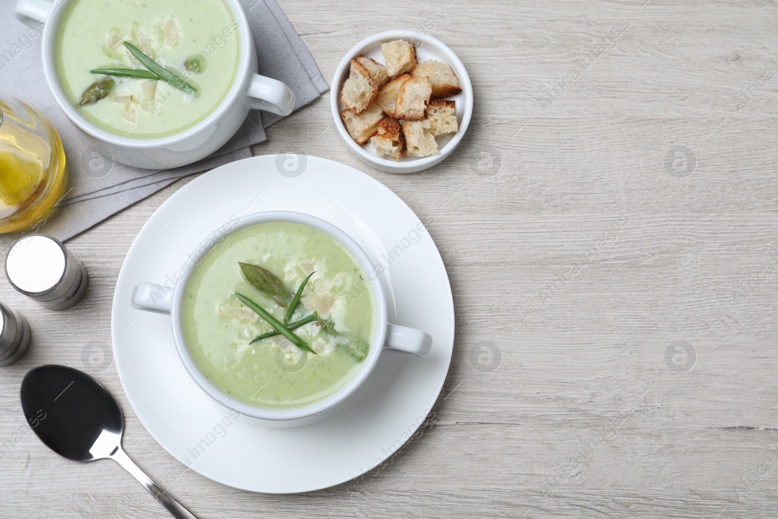 Photo of Delicious asparagus soup with green onion served on white wooden table, flat lay. Space for text