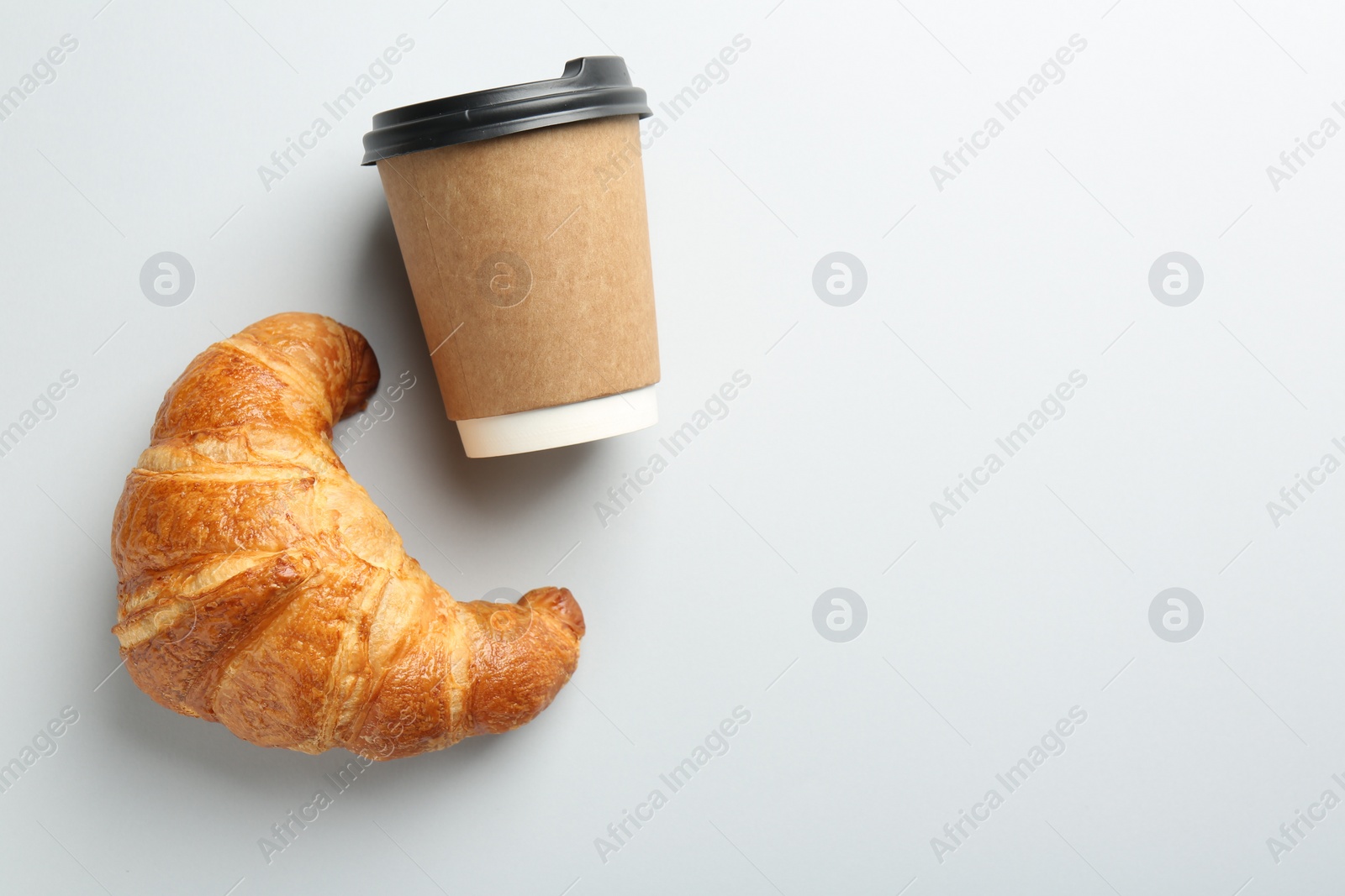 Photo of Delicious fresh croissant and paper cup with coffee on light background, flat lay. Space for text