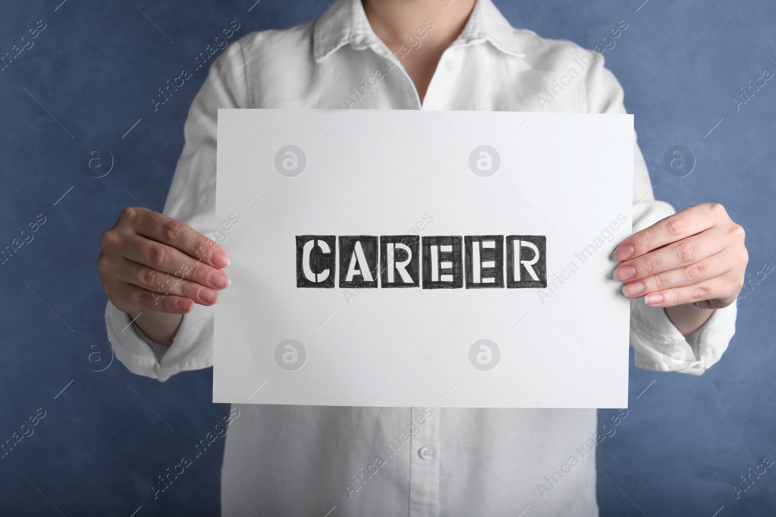 Photo of Woman holding sheet of paper with word CAREER on blue background, closeup