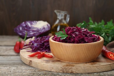 Photo of Tasty red cabbage sauerkraut and ingredients on wooden table. Space for text