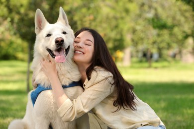 Photo of Teenage girl hugging her white Swiss Shepherd dog in park