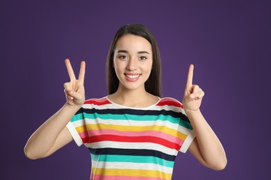 Woman showing number three with her hands on purple background