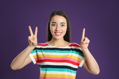 Photo of Woman showing number three with her hands on purple background