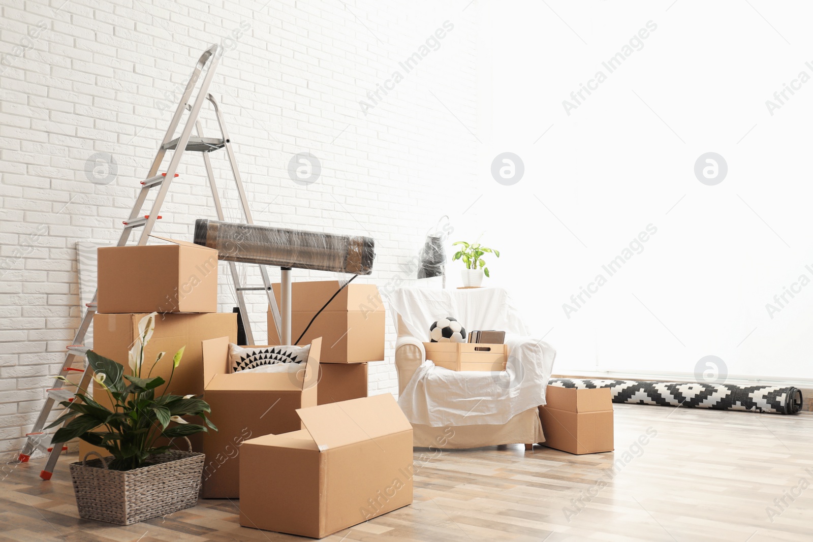 Photo of Cardboard boxes and household stuff in living room. Moving day