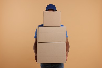 Courier with stack of parcels on light brown background