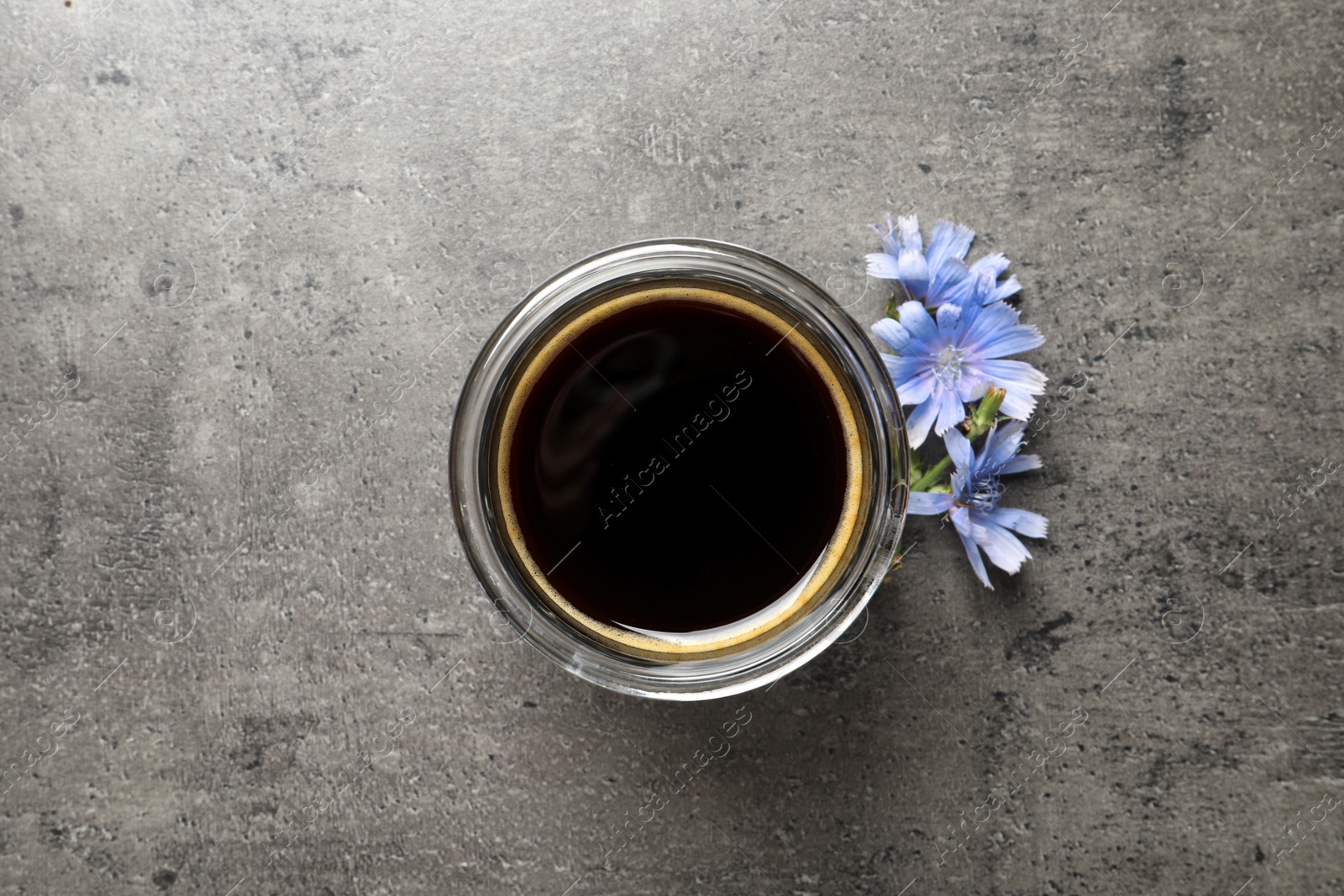 Photo of Delicious chicory drink and flowers on grey table, flat lay