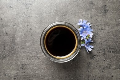 Delicious chicory drink and flowers on grey table, flat lay