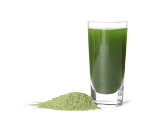 Photo of Wheat grass drink in shot glass and pile of green powder isolated on white