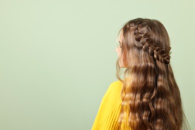 Cute little girl with braided hair on light green background. Space for text