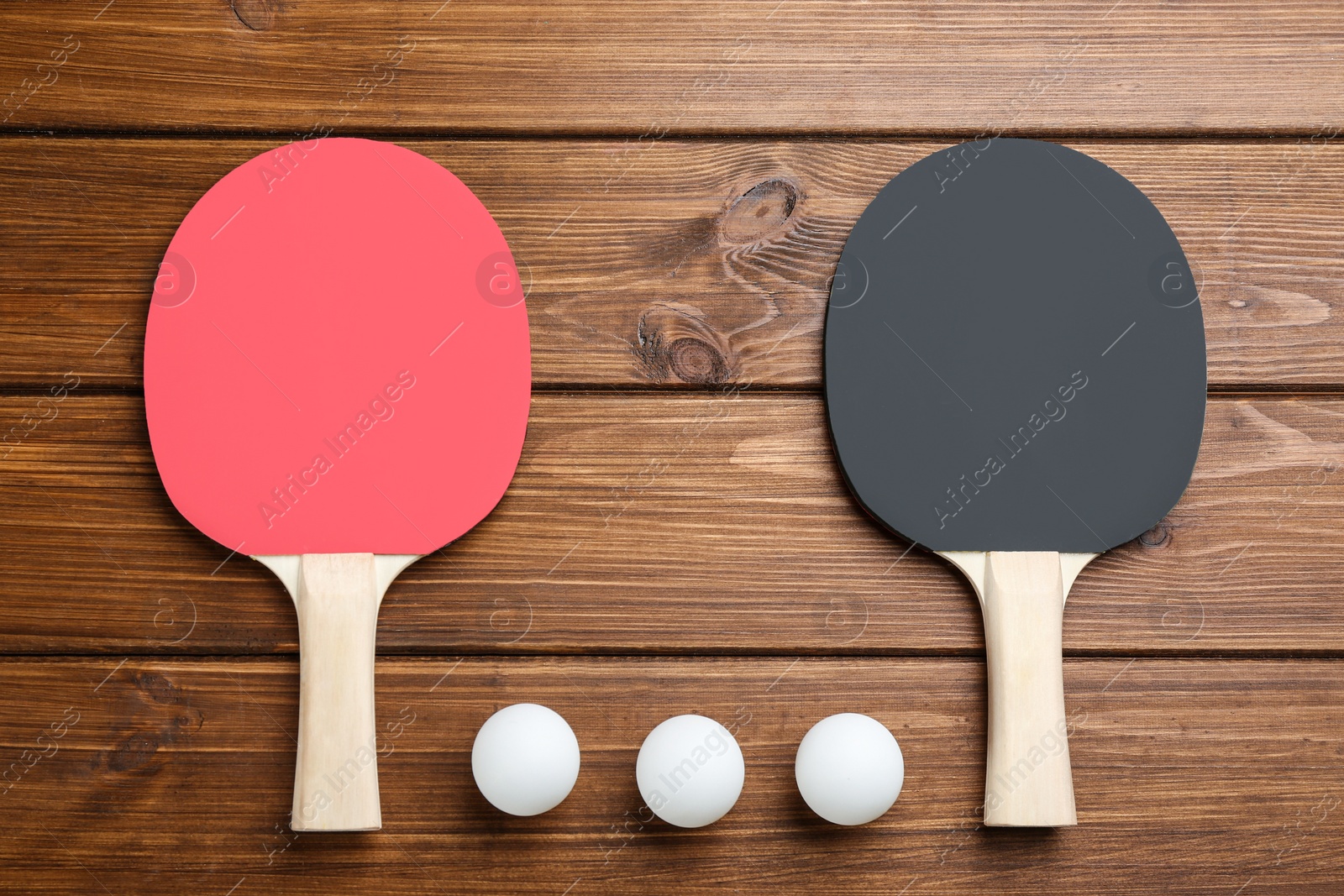 Photo of Ping pong rackets and balls on wooden table, flat lay