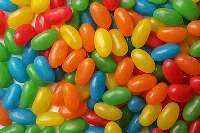 Tasty bright jelly beans as background, top view