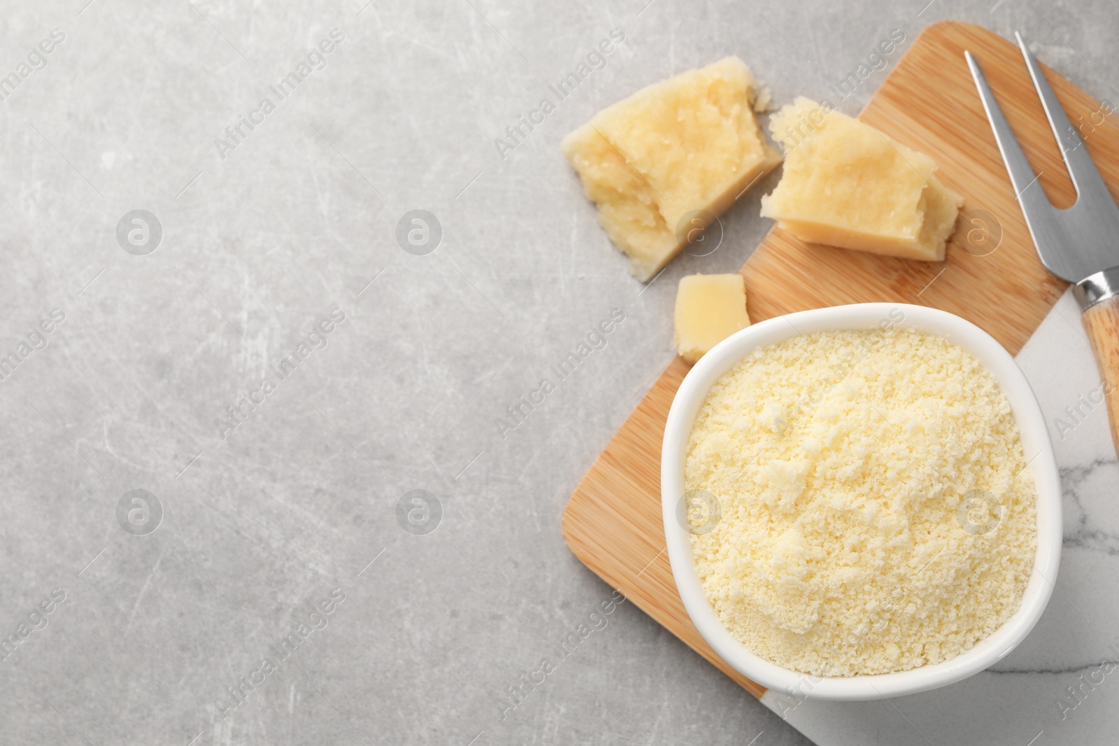 Photo of Parmesan cheese with fork on grey table, flat lay. Space for text