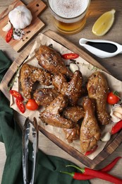 Photo of Tasty chicken glazed in soy sauce and different products on wooden table, flat lay