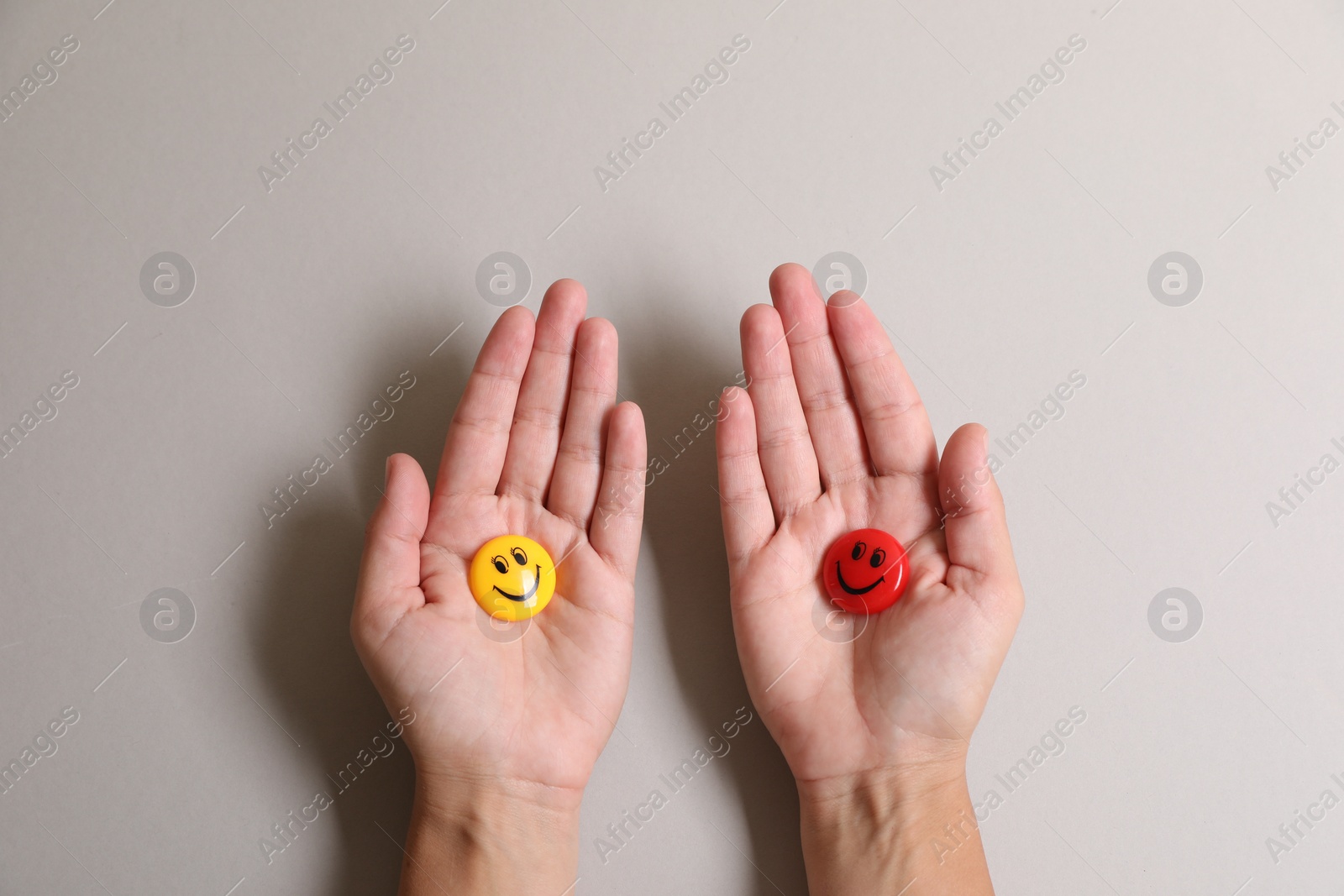 Photo of Choice concept. Woman holding magnets with happy emoticons on light background, closeup