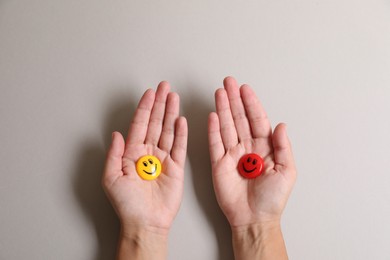 Choice concept. Woman holding magnets with happy emoticons on light background, closeup