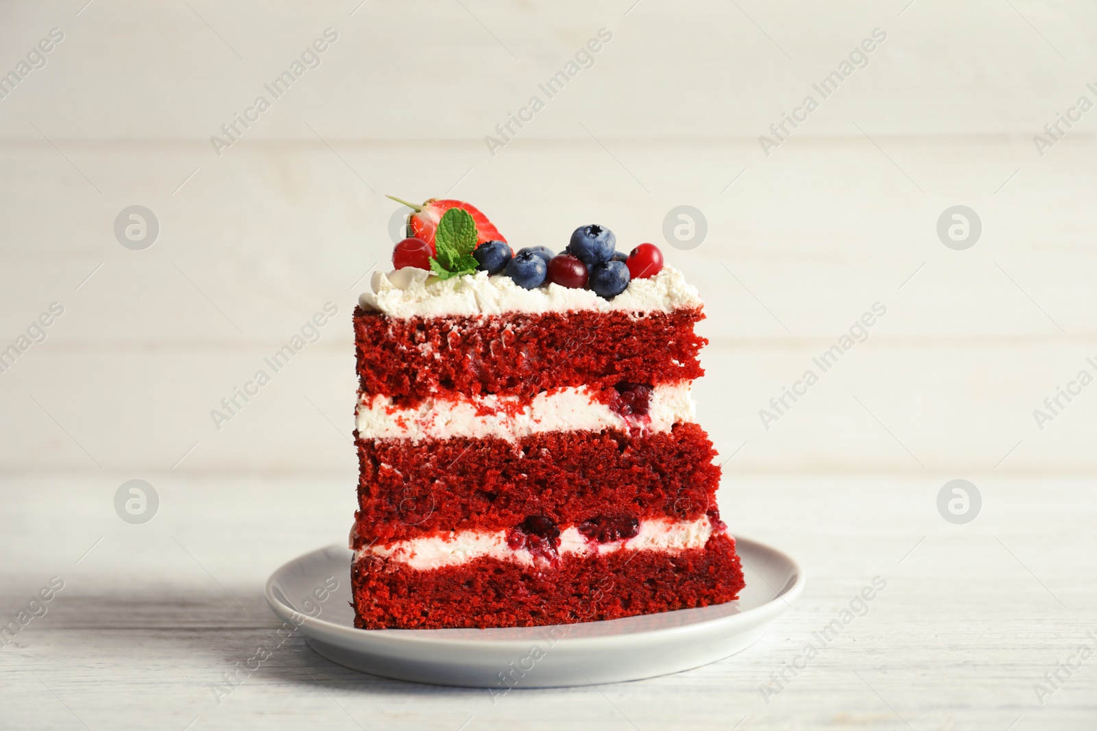 Photo of Plate with piece of delicious homemade red velvet cake on wooden table