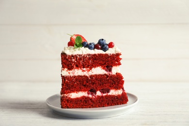 Plate with piece of delicious homemade red velvet cake on wooden table