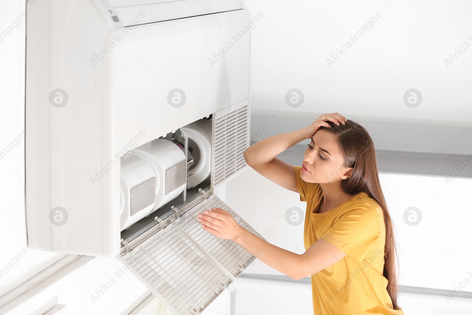 Photo of Young woman fixing air conditioner at home