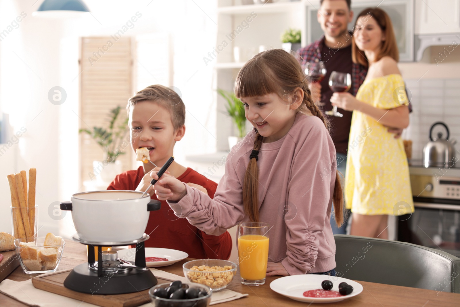 Photo of Happy kids enjoying fondue dinner at home