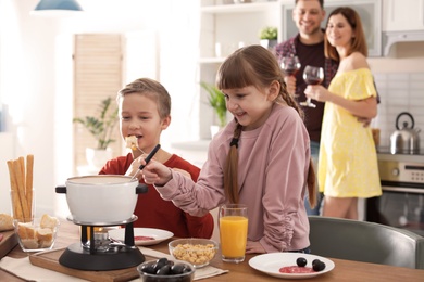 Happy kids enjoying fondue dinner at home