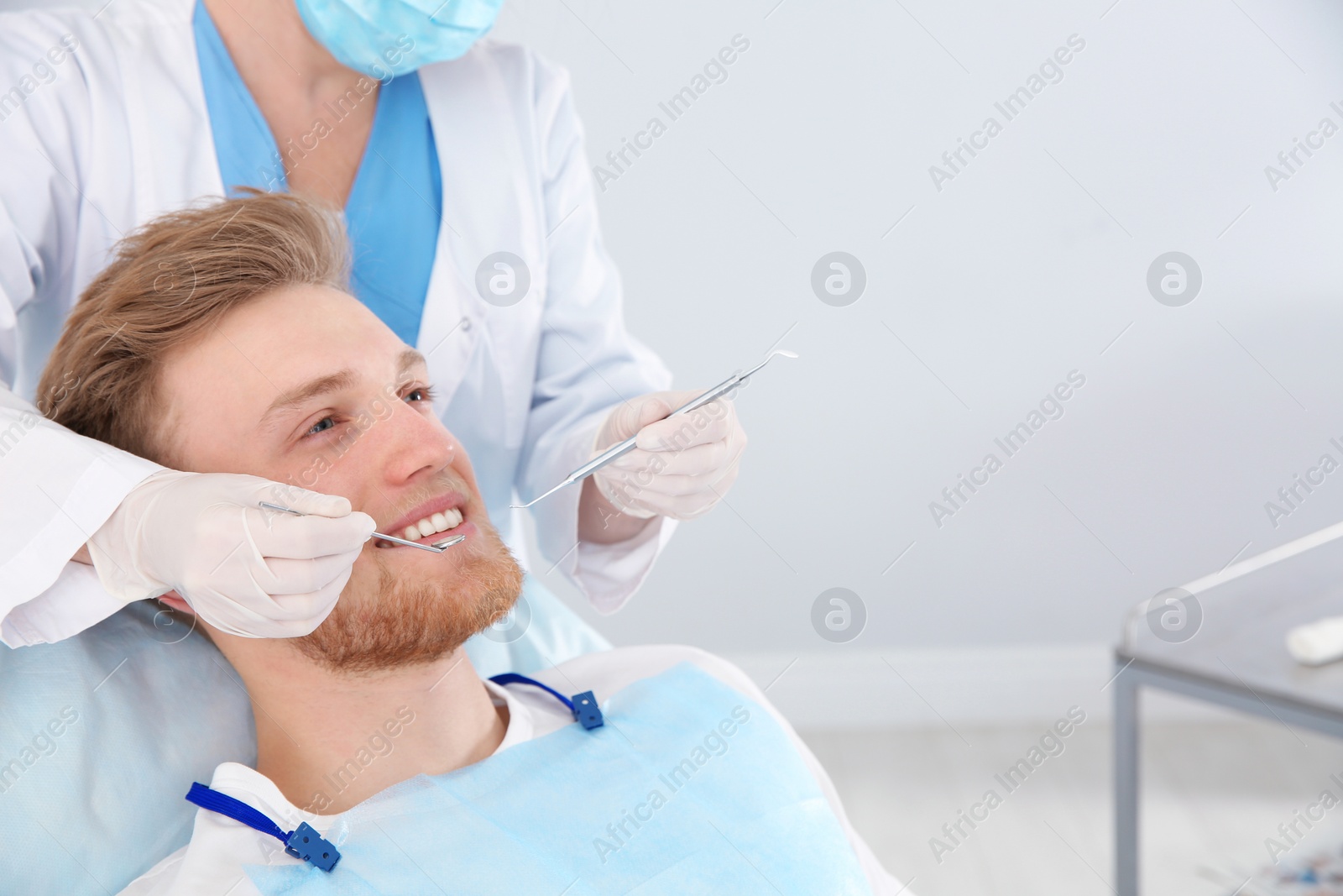 Photo of Dentist examining patient's teeth in modern clinic. Space for text