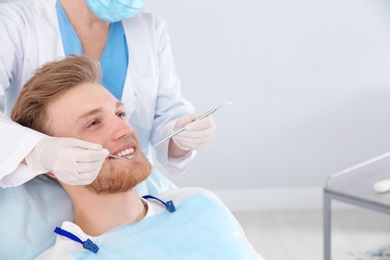 Photo of Dentist examining patient's teeth in modern clinic. Space for text