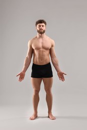 Handsome man with muscular body on light grey background