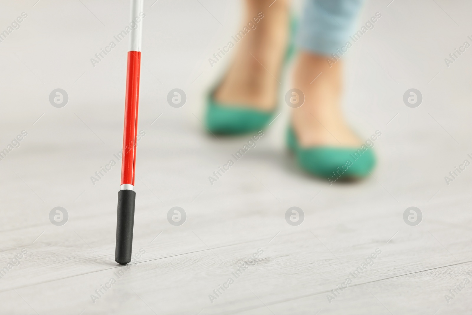 Photo of Blind person with long cane walking indoors, closeup