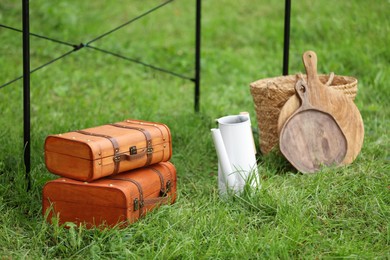 Photo of Suitcases, boards and wicker basket on green grass. Garage sale