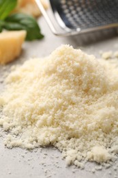 Photo of Pile of grated parmesan cheese on light table, closeup