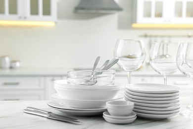 Photo of Different clean dishware, cutlery and glasses on white marble table in kitchen