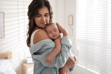 Photo of Happy young mother with her sleeping baby near window at home